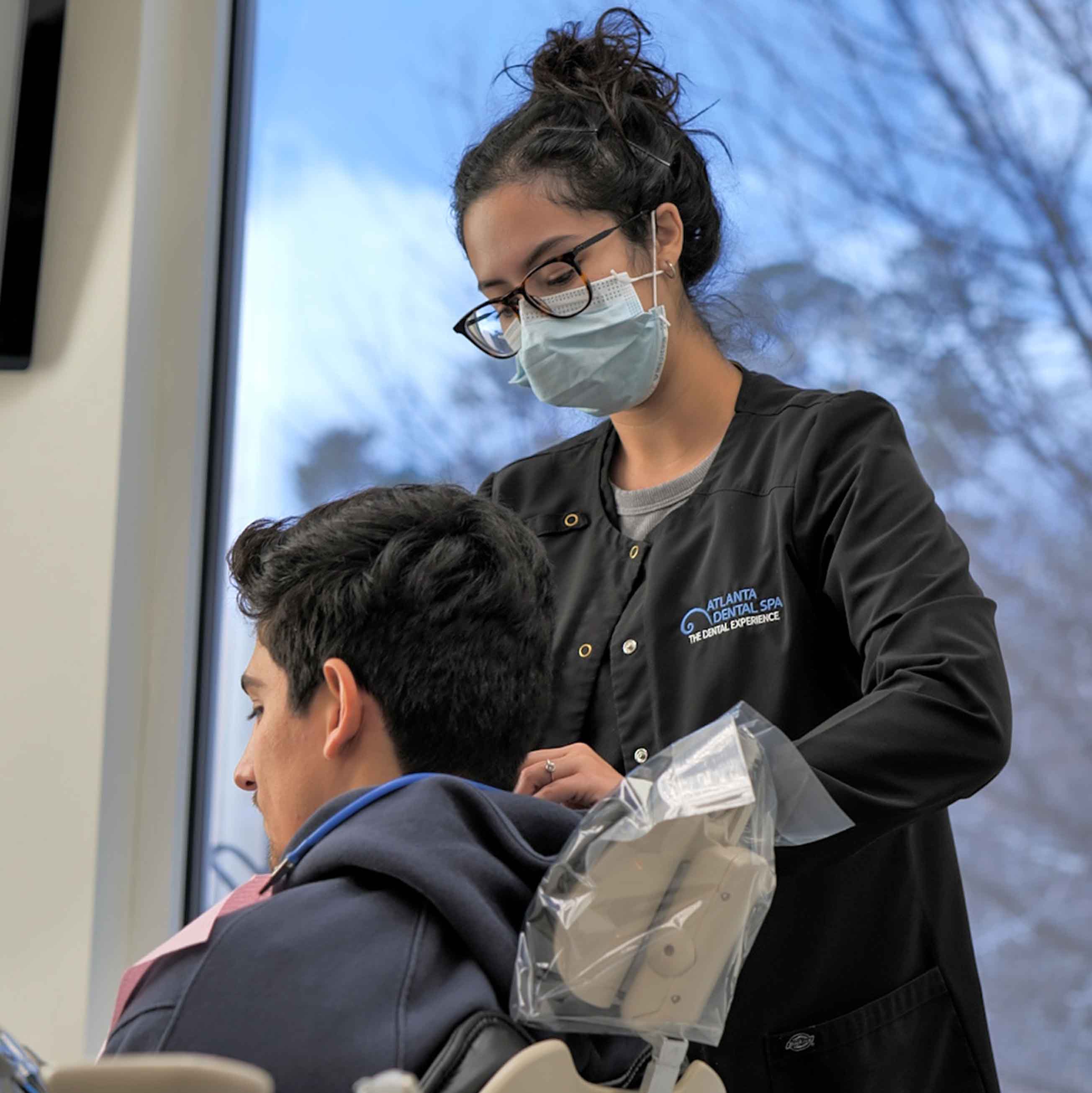 Dental professional at Atlanta Dental Spa providing care to a patient in a modern treatment room.
